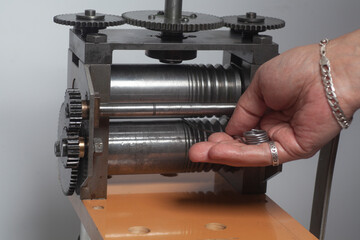 Jeweler at work, process rolling of a silver wire crafting in a jewelery workshop.