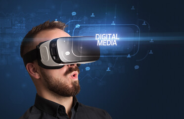 Businessman looking through Virtual Reality glasses with DIGITAL MEDIA inscription, social networking concept