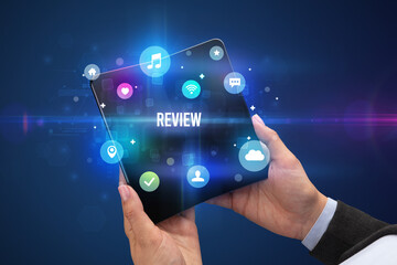 Businessman holding a foldable smartphone with REVIEW inscription, social media concept