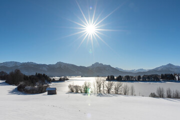 panoramic landscape in winter wirh mountain range and sun on sky