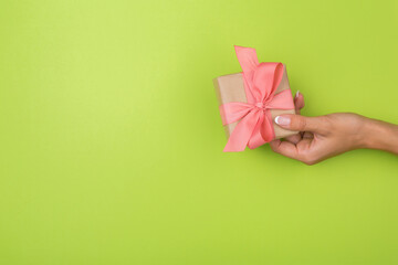Top view of female hands holding a present box package in palms, on green background