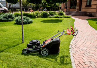 Lawn mower on green grass. Summer garden