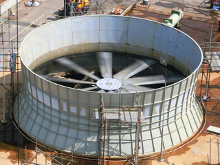 Concrete cooling tower and cooling fan blowing steam on the air