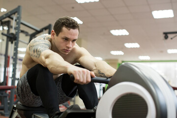 Fototapeta na wymiar Man running rowing exercise in the gym