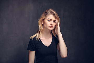 Tired young girl with headache on dark background