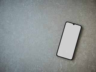 Black mobile smartphone mockup lies on the surface with a blank screen isolated on a porcelain granite ceramic stone background