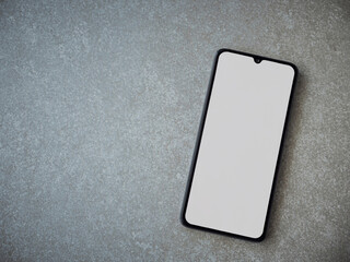 Black mobile smartphone mockup lies on the surface with a blank screen isolated on a porcelain granite ceramic stone background