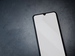 Black mobile smartphone mockup lies on the surface with a blank screen isolated on a dark marble stone background