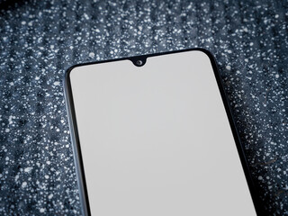 Black mobile smartphone mockup lies on the surface with blank screen isolated on a metallic background