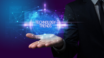 Fototapeta premium Man hand holding TECHNOLOGY TRENDS inscription, technology concept