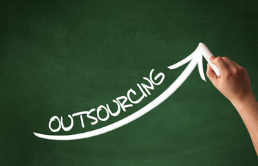 Hand drawing OUTSOURCING inscription with white chalk on blackboard, business concept