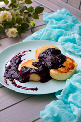 Cottage cheese pancakes with currant and blubbery jam on vintage teal plate