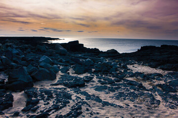 Fototapeta premium Sun setting over a rocky beach
