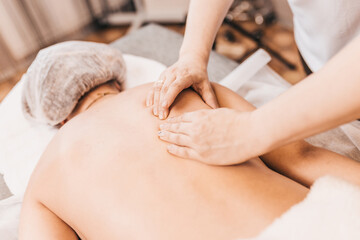 In the massage parlor the masseur hands on the woman back - manual therapy