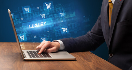 Businessman working on laptop with LUXURY inscription, online shopping concept