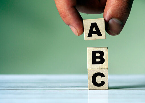 hand puts the cube block with the inscription ABC