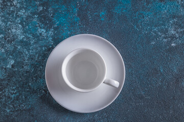 Empty white cup for coffee on blue background,flat lay, copy space.