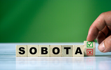hand turns the wooden cube and changes the polish word SOBOTA (english saturday)
