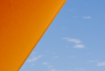 Bottom view of an orange awning with blue sky in the background