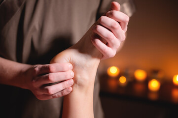 Close-up of a male masseur doing a leg and foot massage in a dark room against the background of candles professional massage in an office with dark light