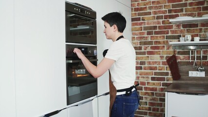 A female baker turn off the oven on modern kitchen