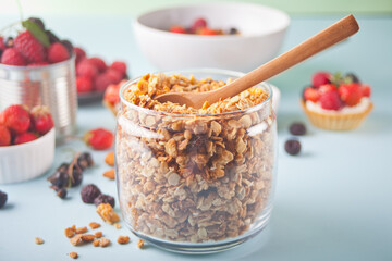 Healthy oat granola muesli cereals in a jar with fresh berries on the background