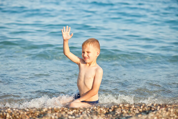 Boy having fun in sea or ocean waves in a summer sunny day. Ocean coast and beach. Active lifestyle and recreation concept