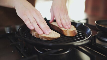 Close-up shot of four slices of baguette are being fried in a grill pan for italian bruschetta.