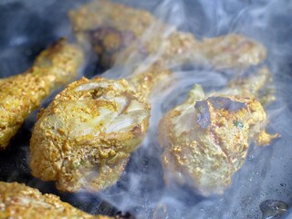 Smokey Chicken tangdi or Tangri kebab or kabab being cooked in a grill pan