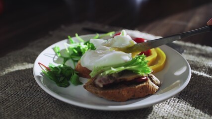 Poached egg on toast. Slicing the the yolk.