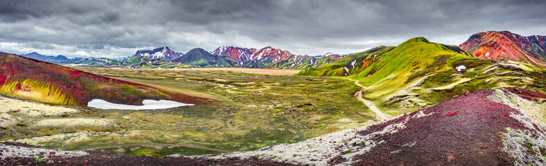 Panoramic unreal magic Icelandic landscape view of colorful rainbow volcanic Landmannalaugar mountains, red and pinky volcanic crater and famous Laugavegur hiking trail with dramatic sky, Iceland © neurobite