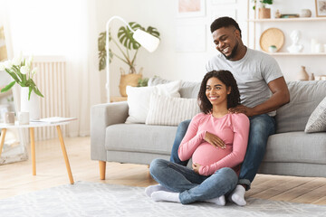 Fototapeta premium Pregnant black woman enjoying while husband massaging her shoulders