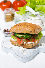 sandwich with salted fish, fresh vegetebles and cream cheese on white wooden board, vertical