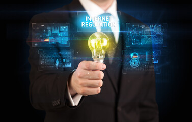 Businessman holding lightbulb with INTERNET REGULATION inscription, online security idea concept