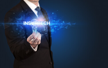Businessman holding light bulb with INSURTECH inscription, innovative technology concept