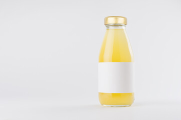 Yellow pineapple juice in glass bottle with gold cap and white blank label mock up on white background with copy space, template for packaging, advertising, design product, branding.