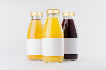 Yellow, red fruit and berries juices collection in glass bottles with cap, white blank labels,...