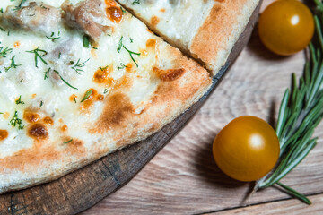 Appetizing pizza on a wooden table surrounded by herbs and spices. The concept of delicious food, restaurants and cafes
