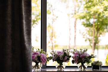 vases of flowers are on window, three large bouquets and one small