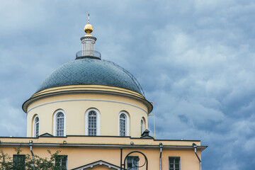 A green dome with elongated arched windows topped with a golden dome against a stormy sky. Capital of the Russian Empire Moscow