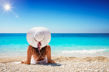 Urlaubskonzept mit einer eleganten Frau in weiß die an einen tropischen Strand liegt, mit...