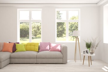 Obraz premium White living room with sofa and summer landscape in window. Scandinavian interior design. 3D illustration
