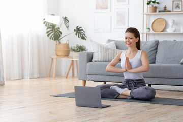 Positive yoga girl doing morning practice in front of laptop