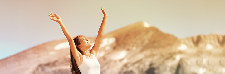Happy free woman excited with arms up enjoying summer sunshine freedom on nature travel outdoor mountains landscape banner panorama. Smiling Asian girl.