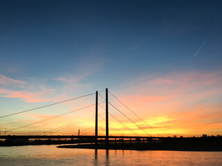 Fototapeta na wymiar Colourful sunset on the Rhine with bridge in the background