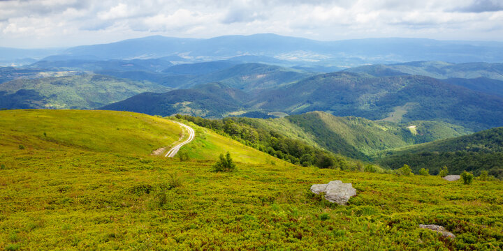 travel carpathian mountains in summer. road through green grassy meadows in the distance. idyllic landscape with clouds on the blue sky.