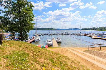 Sailing boats on lake shore in Krzyze village port on sunny summer day, Mazury Lake District, Poland