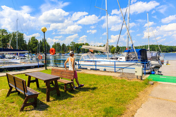 Young female tourist standing near sailing boats at Lake Beldany in port Wierzba on summer sunny day, Mazury Lake District, Poland © pkazmierczak