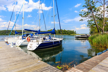 Sailing boats anchoring at pier of Lake Beldany in port Wierzba on summer sunny day, Mazury Lake District, Poland © pkazmierczak