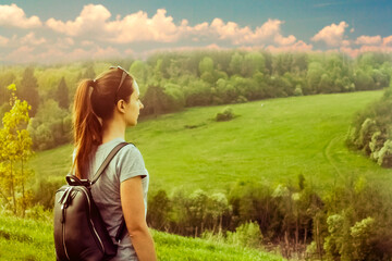 Beautiful meadow and hill landscape with tourist girl. Portrait of woman with backpack standing on the hill